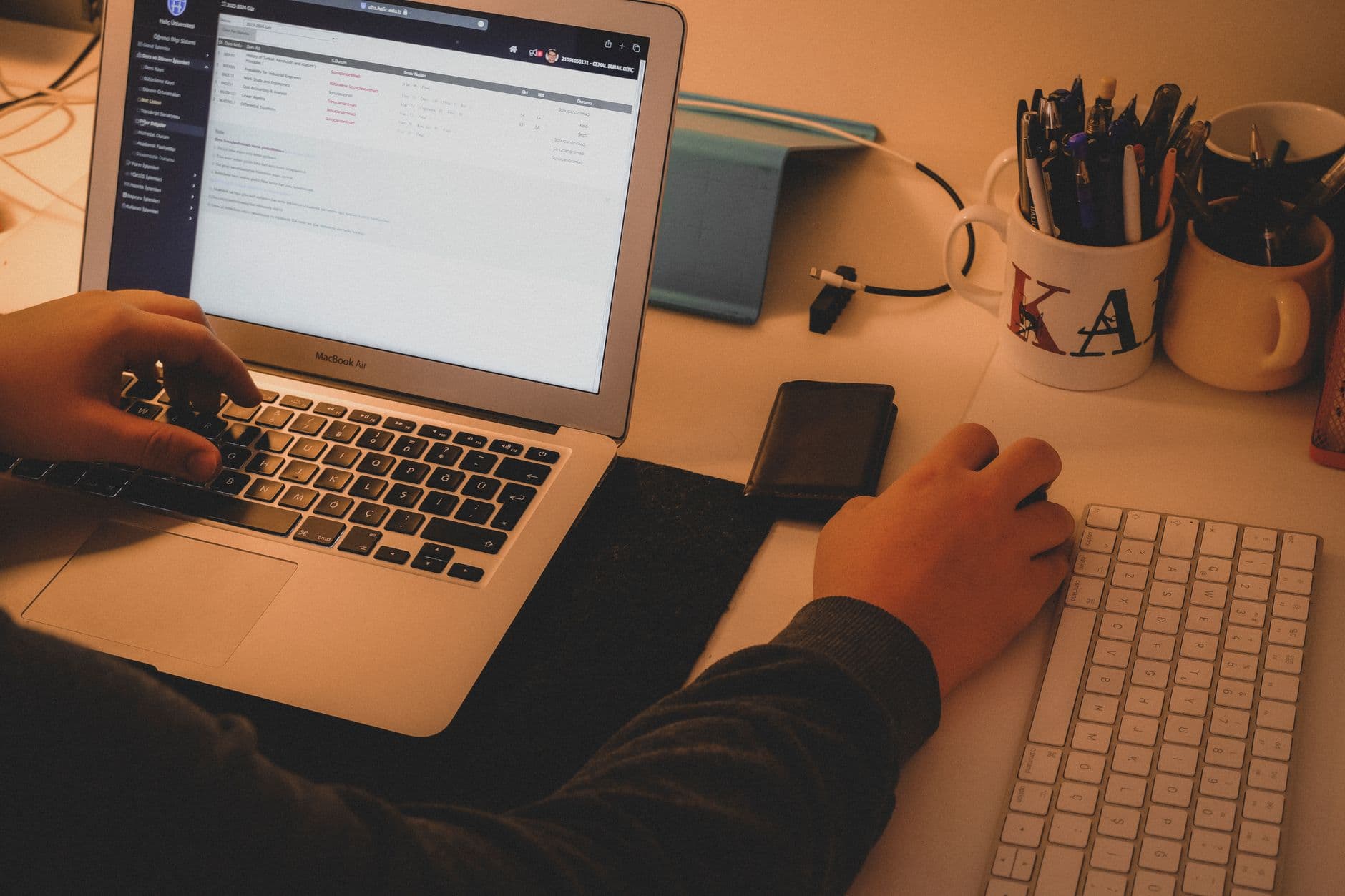 Profissional trabalhando em casa com notebook, fatura de internet e equipamentos sobre a mesa.