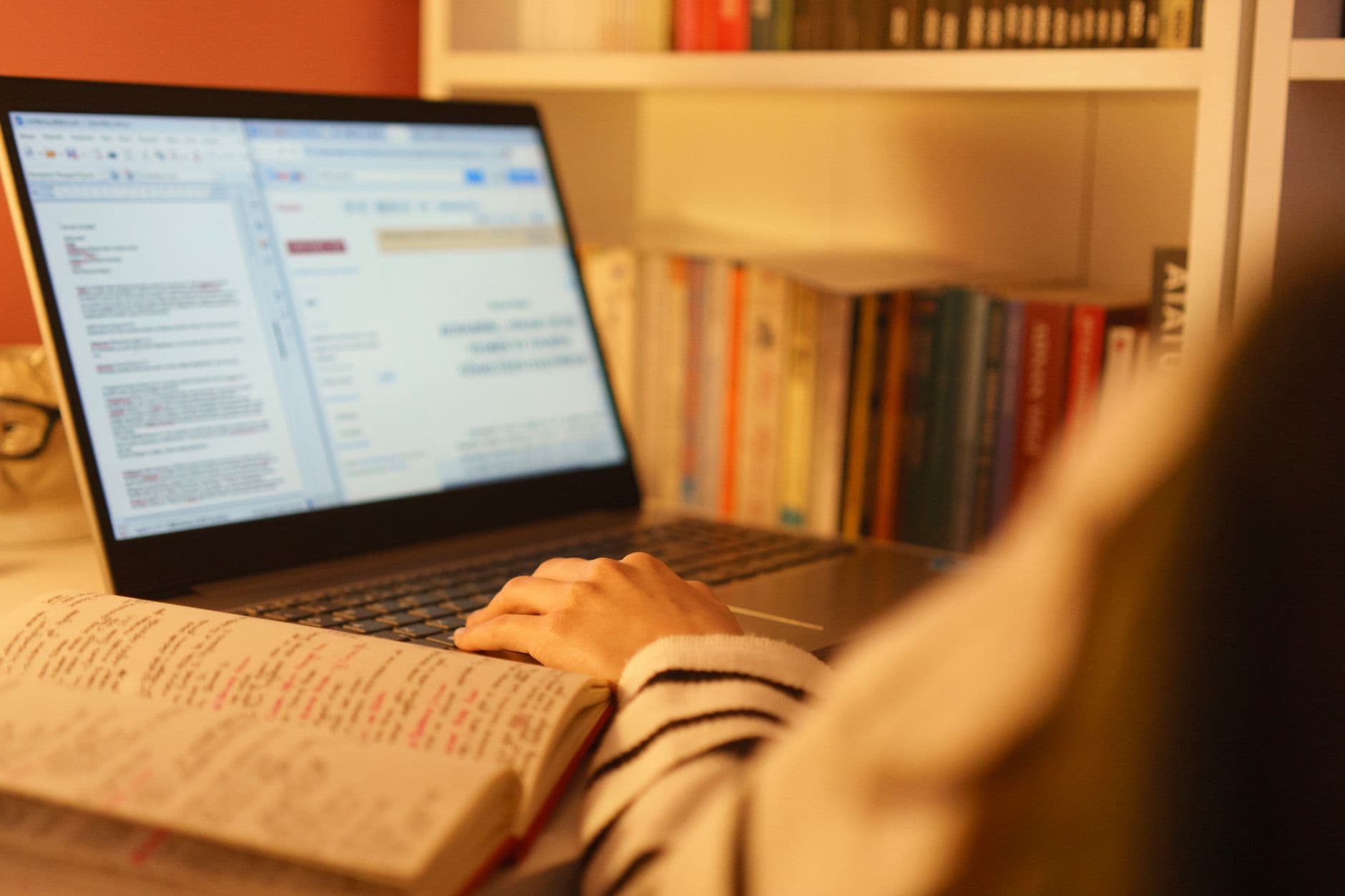 Pessoa estudando em um computador portátil em um escritório em casa organizado.