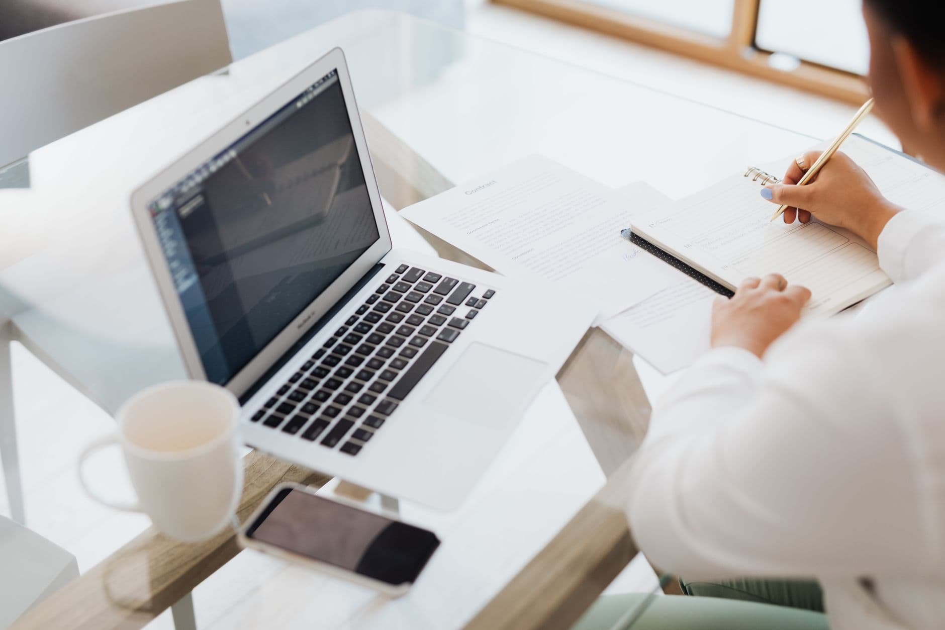 Profissional trabalhando em casa com laptop, documentos e cadeira ergonômica