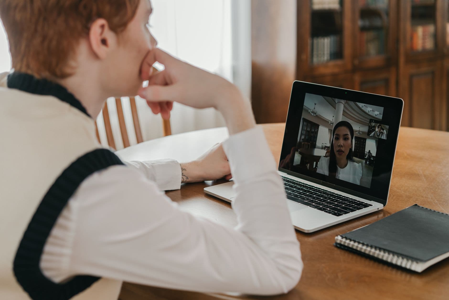 Como validar uma oferta de emprego remoto suspeita Man participates in a virtual meeting on his laptop at home, highlighting remote communication.