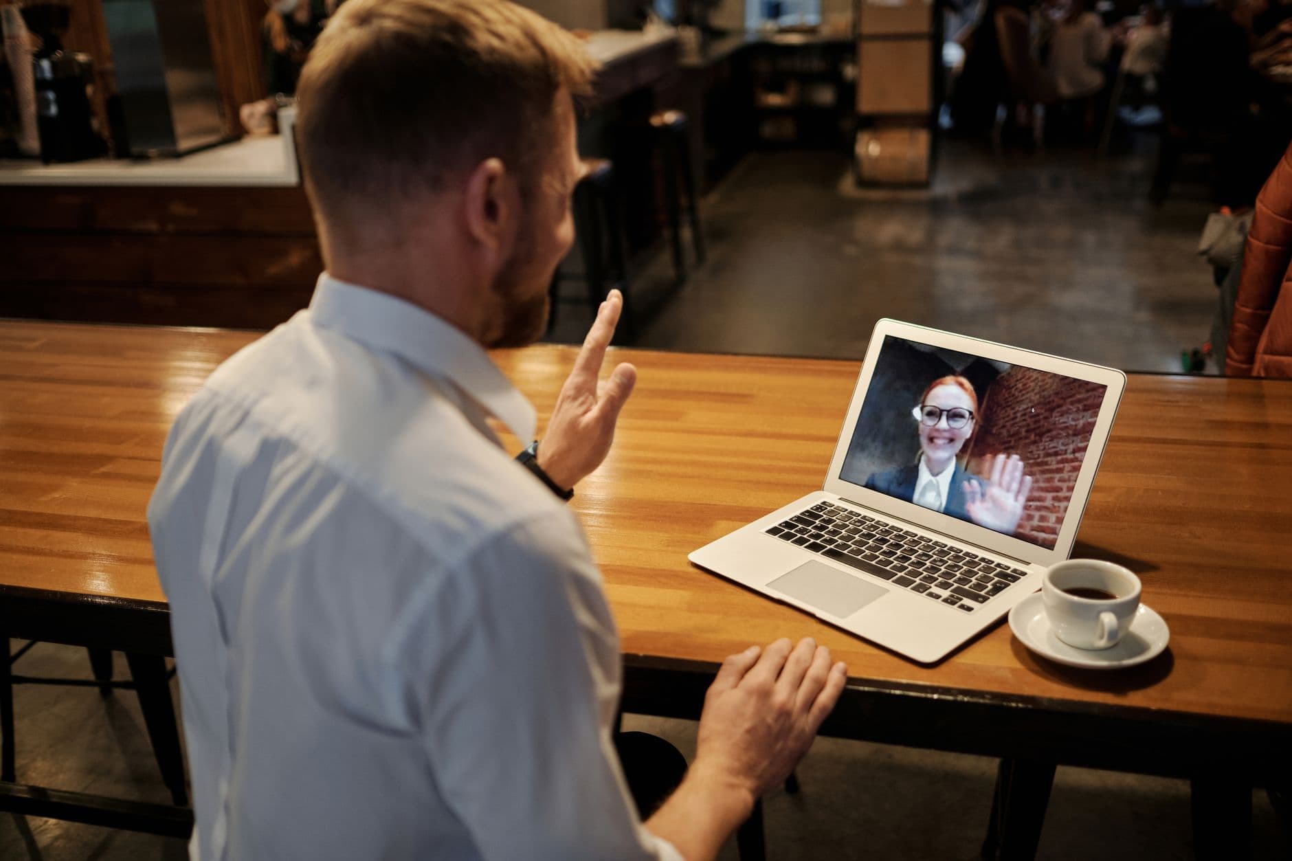 Comunidades online para crescer na carreira remota Business meeting conducted virtually in a cozy cafe setting via laptop.