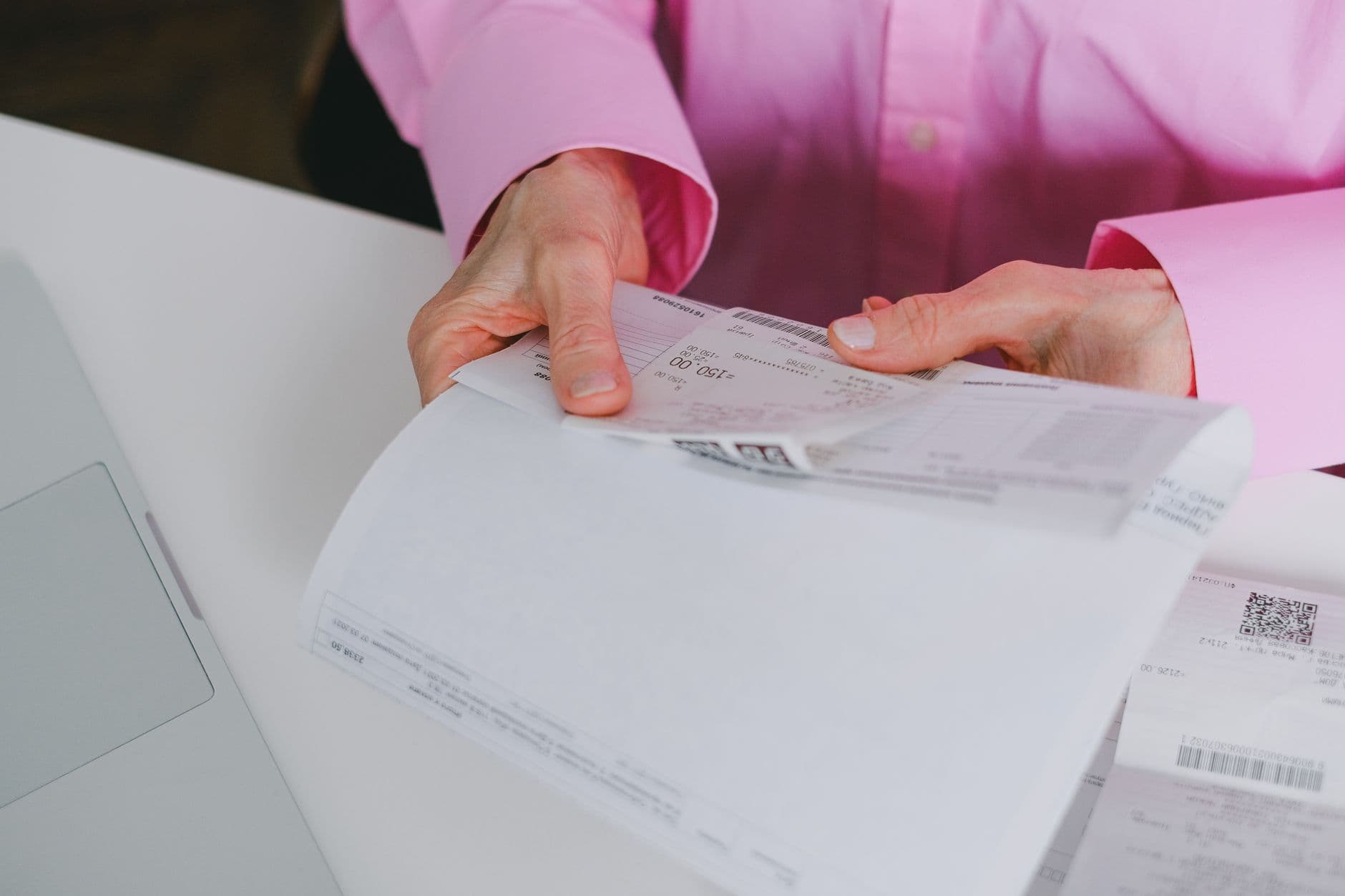 Freelancer internacional: como emitir invoice Business person handling paper receipts, meticulously organized.