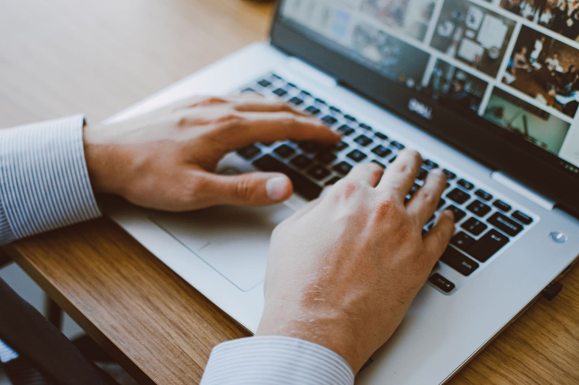Como escolher o monitor ideal para home office Close-up of a man's hands typing on a laptop keyboard, ideal for illustrating remote work or digital communication.