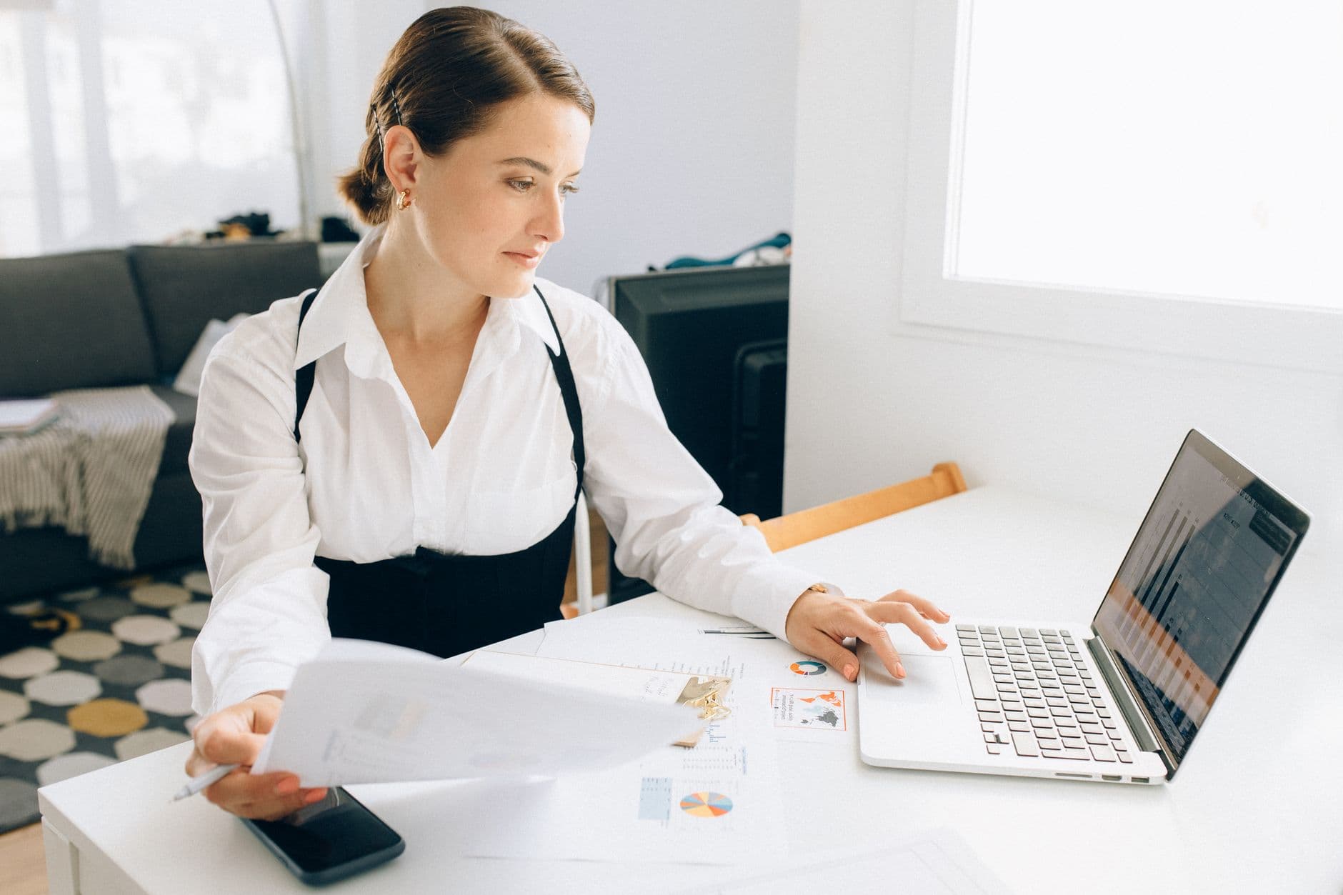 Profissional analisando gráficos em um notebook diante de uma mesa de home office