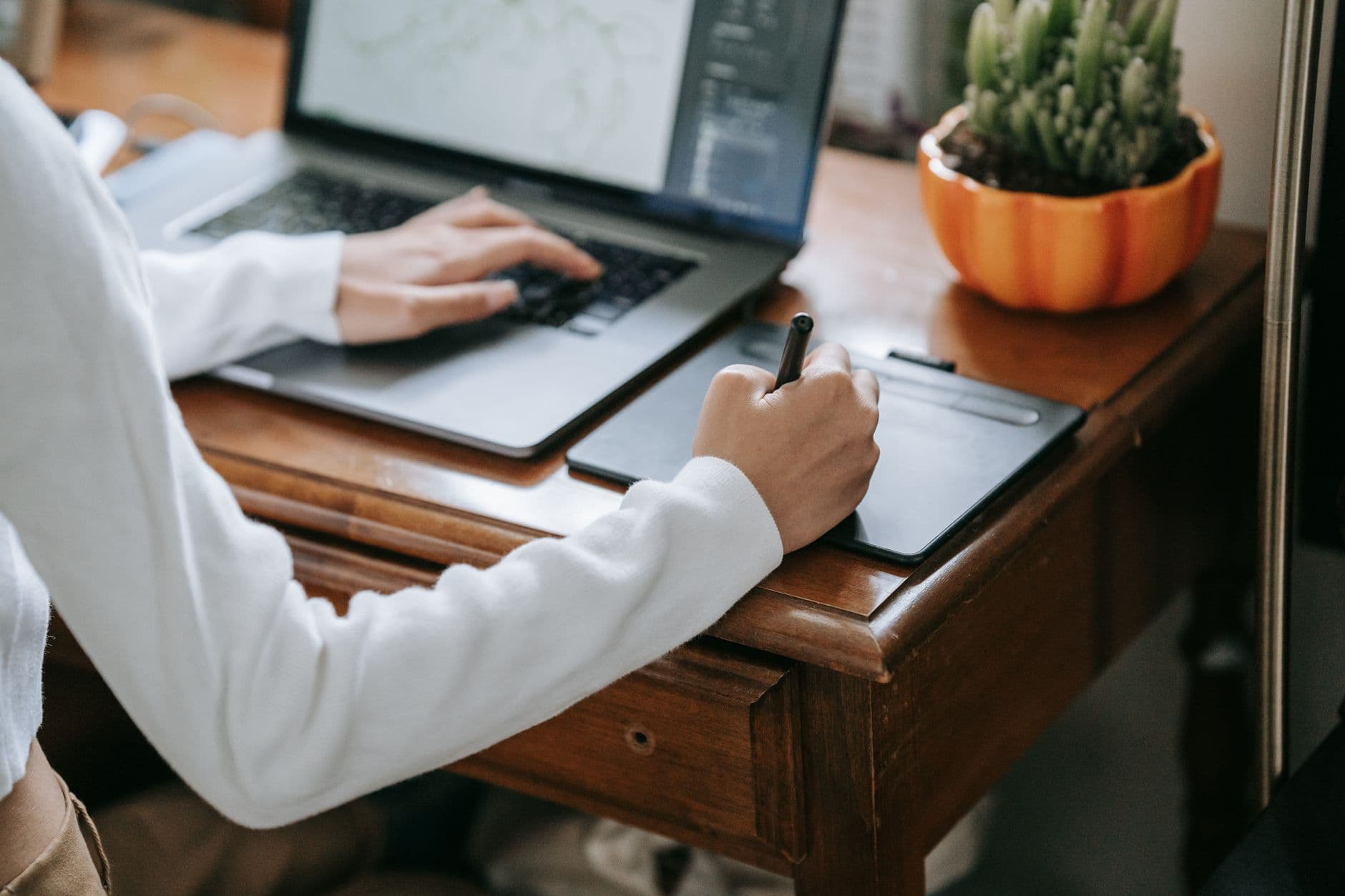 Designer gráfico trabalhando em um laptop com referências visuais sobre a mesa em um home office